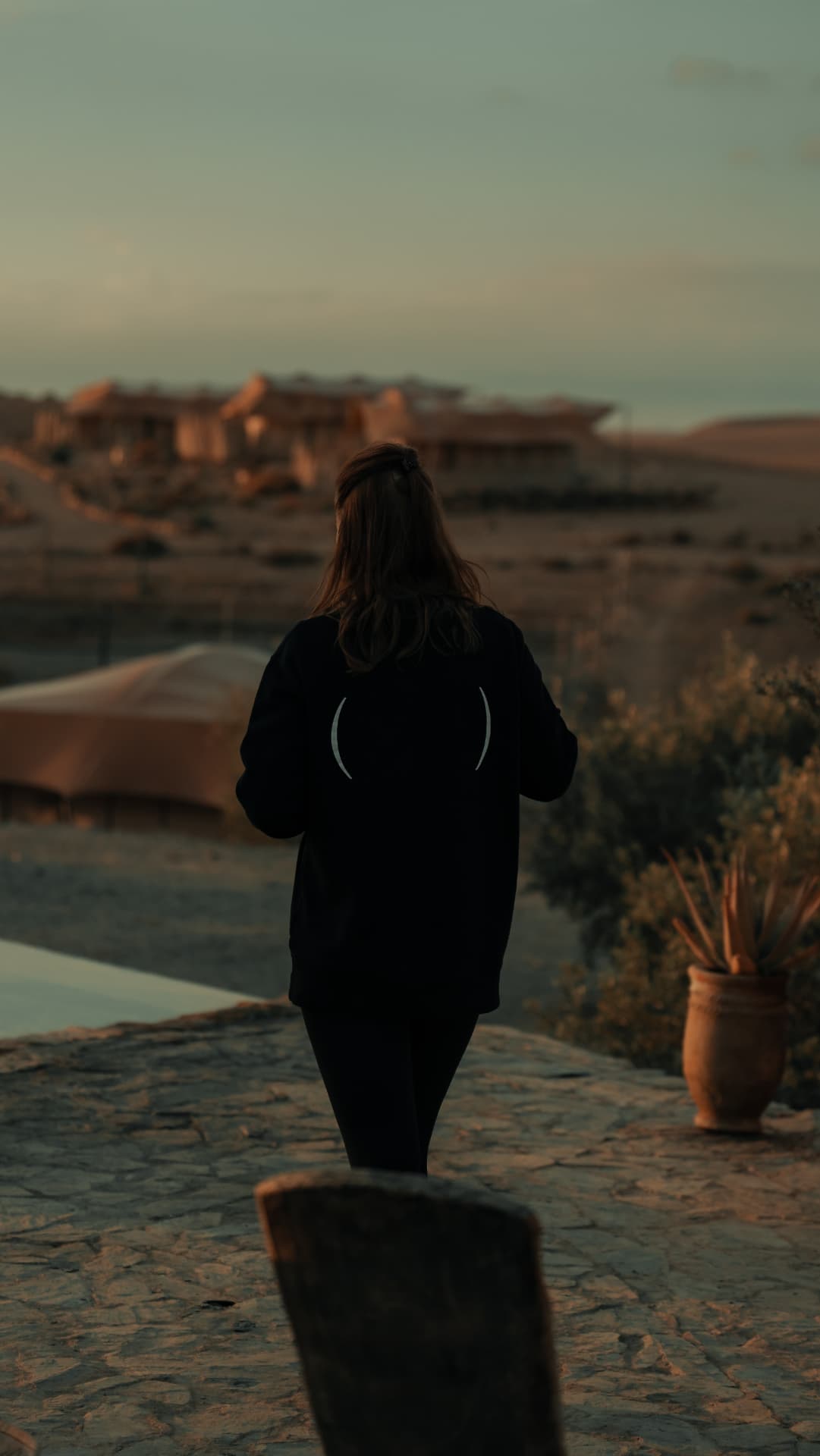 A guest walking through the desert camp at sunset